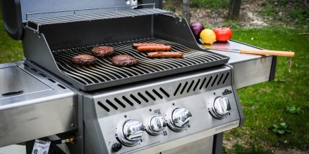 A gas grill with various foods cooking